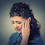 Tinnitus. Closeup sick female having ear pain touching painful head